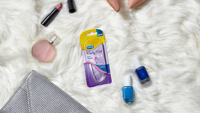 A package of Gikoo Party Fizz hand sanitizer sits on a white faux fur surface, surrounded by beauty props including a pink compact, blue nail polish, and a silver clutch.